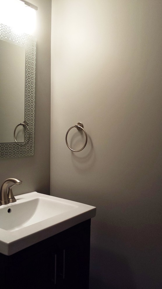 Basement - mid-sized transitional 3/4 and underground vinyl floor and brown floor basement idea with furniture-like cabinets, dark wood cabinets, a two-piece toilet, gray walls and solid surface countertops