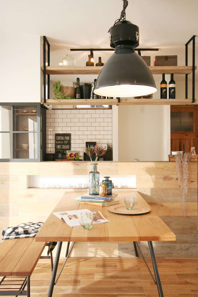 This is an example of an industrial dining room in Other with white walls, medium hardwood floors and brown floor.