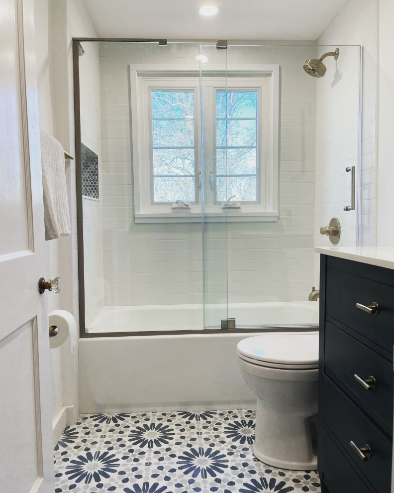 На фото: ванная комната среднего размера в стиле модернизм с синими фасадами, ванной в нише, душем над ванной, унитазом-моноблоком, белой плиткой, плиткой кабанчик, белыми стенами, полом из керамической плитки, врезной раковиной, столешницей из искусственного кварца, душем с раздвижными дверями, белой столешницей, тумбой под одну раковину, напольной тумбой и душевой кабиной