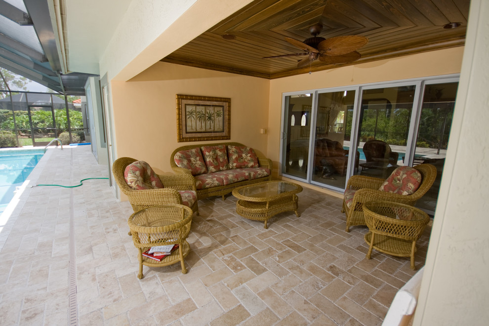 Photo of a tropical backyard patio in Miami with tile and a roof extension.