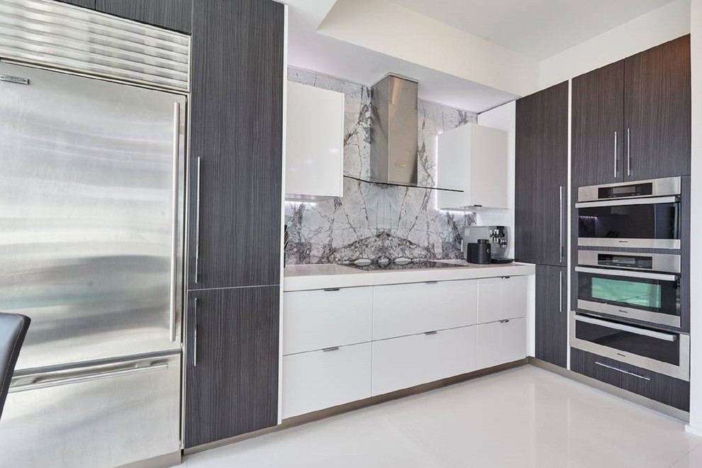 Photo of a mid-sized contemporary galley open plan kitchen in Toronto with a drop-in sink, flat-panel cabinets, white cabinets, marble benchtops, grey splashback, stone tile splashback, stainless steel appliances, marble floors and with island.