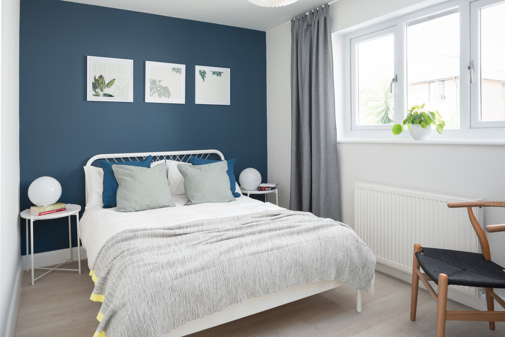 Design ideas for a scandinavian guest bedroom in London with white walls, light hardwood floors and beige floor.