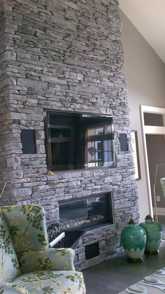 Home design - large transitional open concept medium tone wood floor home design idea in Toronto with beige walls, a standard fireplace, a stone fireplace and a wall-mounted tv