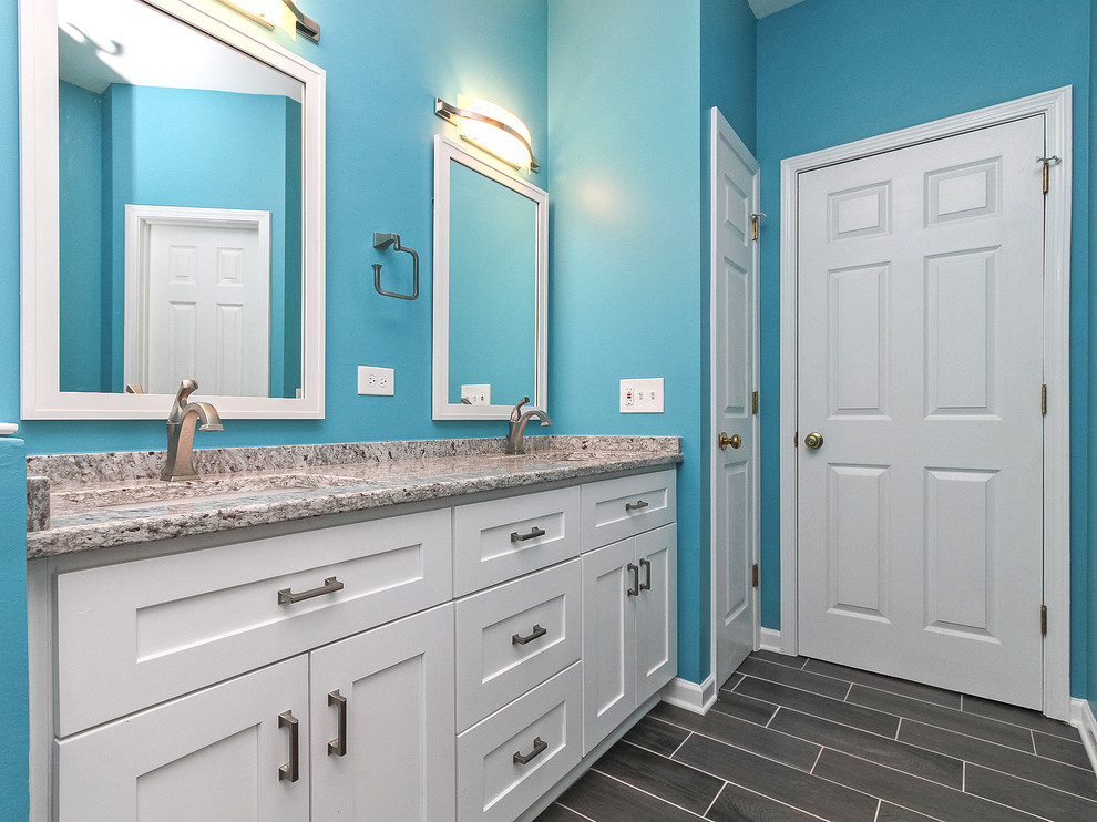 Mid-sized beach style master bathroom in Charlotte with shaker cabinets, white cabinets, an open shower, a two-piece toilet, brown tile, ceramic tile, blue walls, ceramic floors, an undermount sink and granite benchtops.