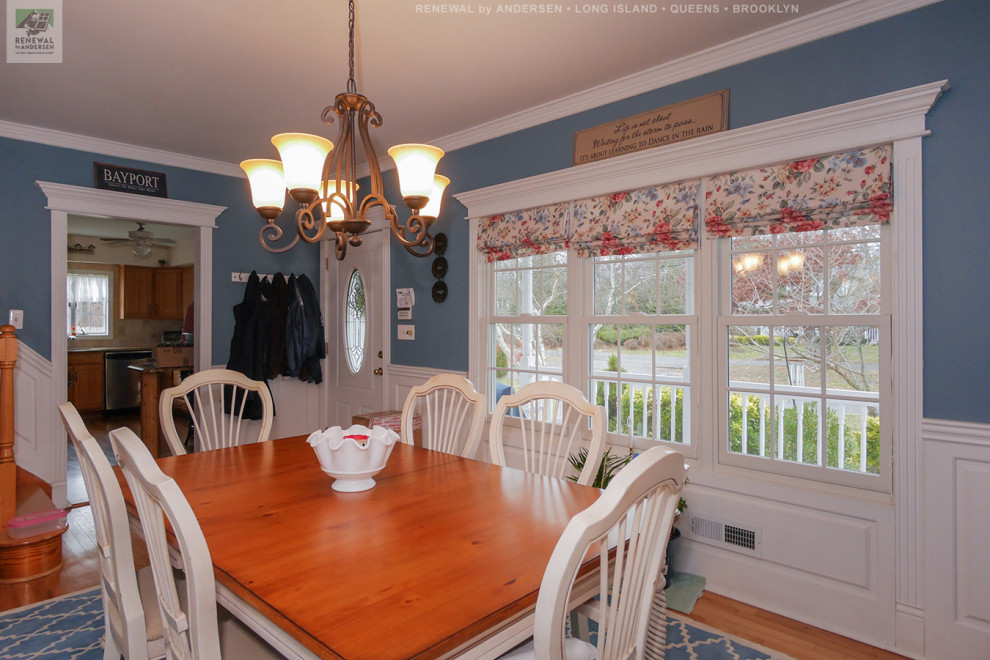 Cette photo montre une salle à manger fermée et de taille moyenne avec un mur bleu, un sol en bois brun, aucune cheminée, un sol multicolore et boiseries.