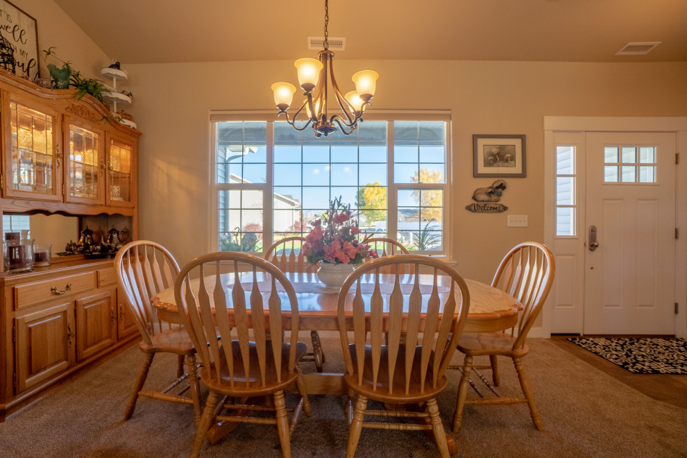 Cette image montre une salle à manger ouverte sur la cuisine traditionnelle de taille moyenne avec un mur beige, moquette, une cheminée standard, un manteau de cheminée en pierre de parement, un sol beige et un plafond voûté.