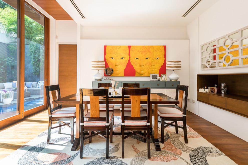 Photo of an asian separate dining room in Singapore with white walls, medium hardwood floors and brown floor.