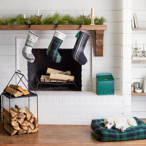 Holiday Decor Ideas for Dog Lovers -White brick firepalce with green plai stocking hanging from mantle.  White dog lying on green and navy plaid dog bed