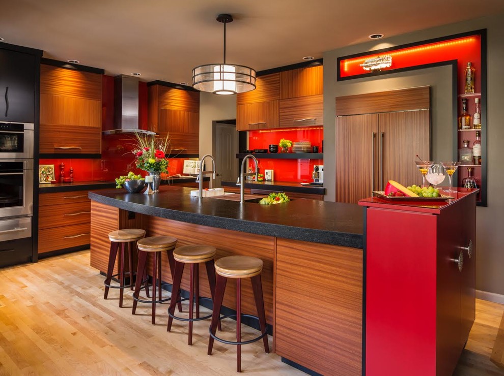 Photo of a large contemporary u-shaped eat-in kitchen in Portland with flat-panel cabinets, medium wood cabinets, solid surface benchtops, red splashback, glass sheet splashback, panelled appliances, light hardwood floors, with island, a double-bowl sink and beige floor.