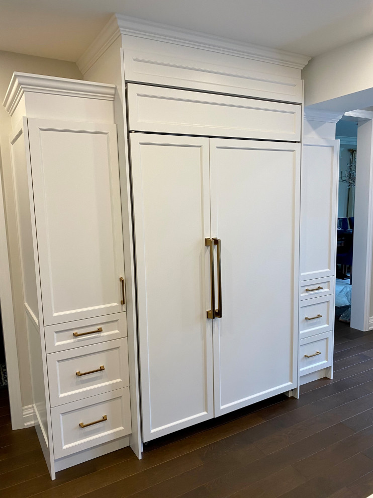 Inspiration for a large transitional medium tone wood floor kitchen remodel in Toronto with an undermount sink, recessed-panel cabinets, white cabinets, quartz countertops, white backsplash, porcelain backsplash, paneled appliances, two islands and white countertops