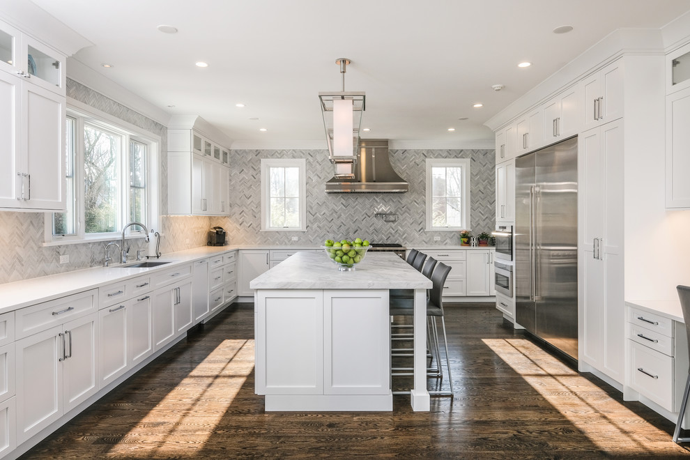 Design ideas for a large traditional kitchen in New York with with island, an undermount sink, shaker cabinets, white cabinets, grey splashback, stainless steel appliances, dark hardwood floors, brown floor and white benchtop.