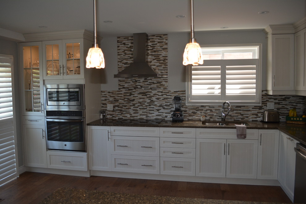 Example of a mid-sized transitional l-shaped medium tone wood floor eat-in kitchen design in Toronto with shaker cabinets, white cabinets, stainless steel appliances, a double-bowl sink, multicolored backsplash, matchstick tile backsplash, a peninsula and granite countertops
