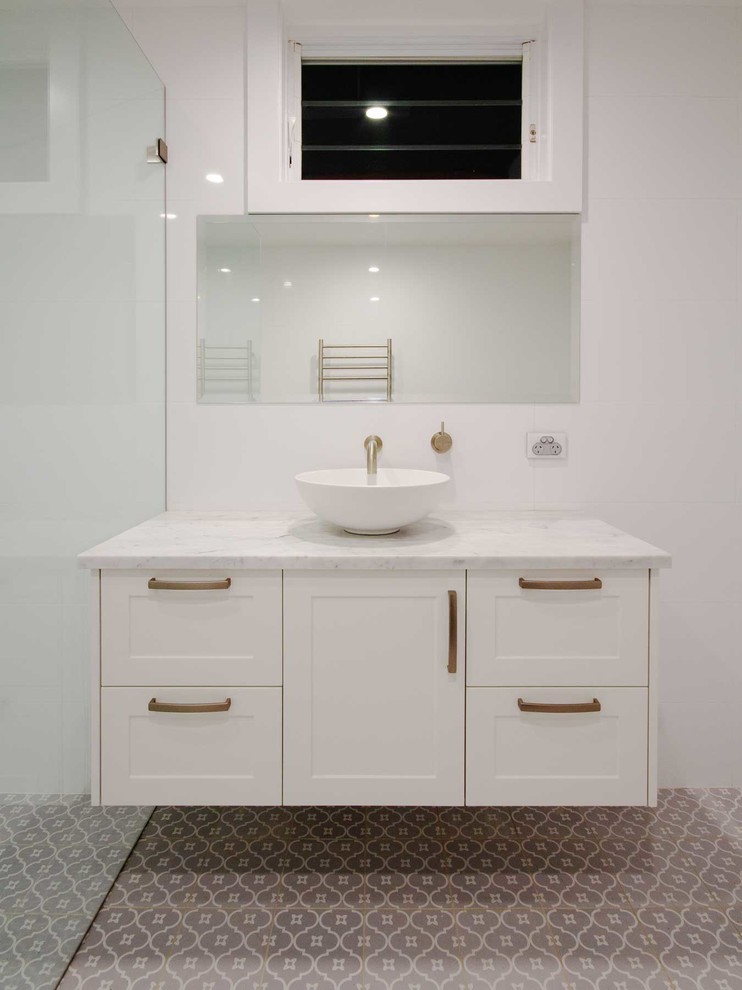 This is an example of a mid-sized traditional master bathroom in Sydney with shaker cabinets, white cabinets, white tile, ceramic tile, white walls, porcelain floors, a vessel sink, engineered quartz benchtops, grey floor, an open shower and white benchtops.