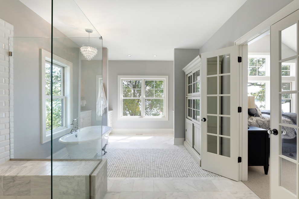 Inspiration for an expansive beach style master bathroom in Minneapolis with shaker cabinets, white cabinets, a claw-foot tub, a corner shower, a two-piece toilet, white tile, porcelain tile, an undermount sink, marble benchtops, a hinged shower door, grey walls, marble floors and white floor.