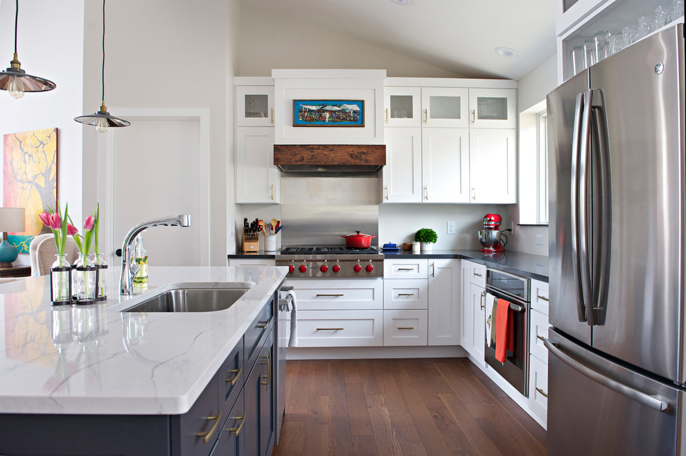 Inspiration for a large transitional l-shaped medium tone wood floor open concept kitchen remodel in Indianapolis with an undermount sink, shaker cabinets, white cabinets, quartz countertops, gray backsplash, stainless steel appliances and an island