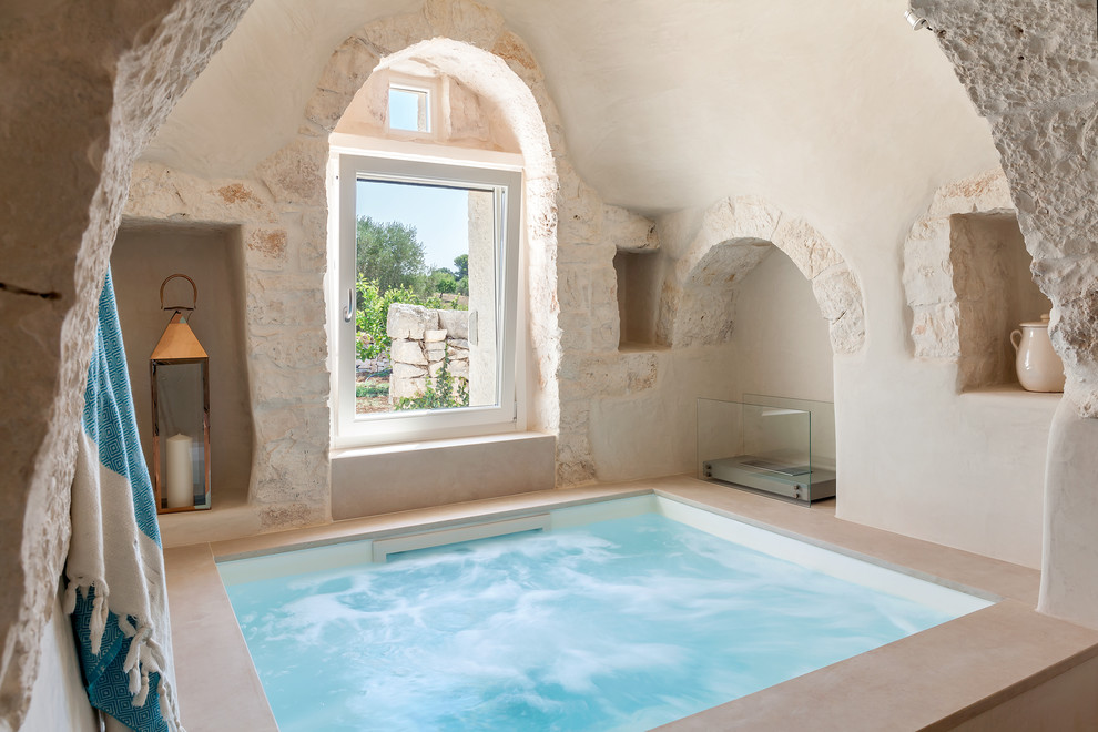 This is an example of a small mediterranean indoor rectangular natural pool in Other with a hot tub.