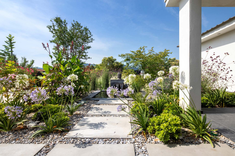 This is an example of a large contemporary front yard full sun garden in Other with with pond and gravel.