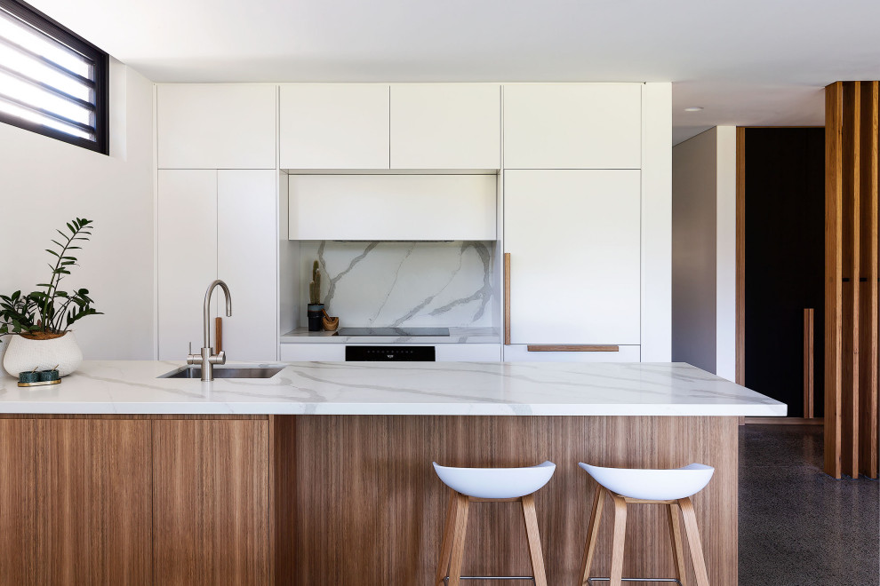 Design ideas for a contemporary galley kitchen in Sydney with an undermount sink, flat-panel cabinets, white cabinets, white splashback, panelled appliances, concrete floors, with island, grey floor and white benchtop.