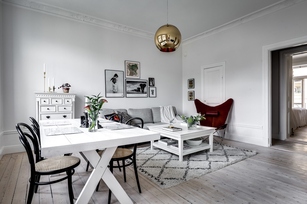 Scandinavian open concept family room in Stockholm with white walls, light hardwood floors and grey floor.