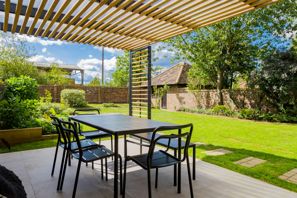 Diseño de jardín moderno de tamaño medio en patio trasero con pérgola, exposición total al sol y adoquines de piedra natural
