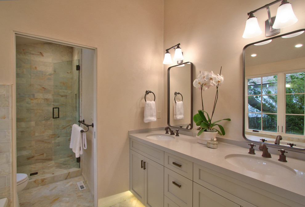 Photo of a mid-sized transitional master bathroom in Other with shaker cabinets, white cabinets, a drop-in tub, a corner shower, beige tile, marble, beige walls, porcelain floors, an undermount sink, solid surface benchtops, beige floor and a hinged shower door.