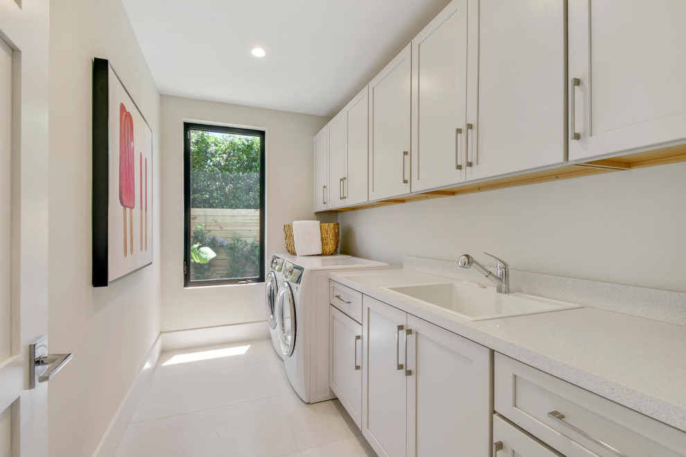 Design ideas for a mid-sized modern dedicated laundry room in Miami with a drop-in sink, shaker cabinets, white cabinets, granite benchtops, white walls, porcelain floors, a side-by-side washer and dryer, white floor and white benchtop.