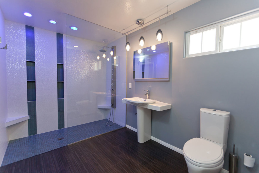 This is an example of a mid-sized modern 3/4 bathroom in Los Angeles with a pedestal sink, a curbless shower, a two-piece toilet, multi-coloured tile, mosaic tile, blue walls and porcelain floors.