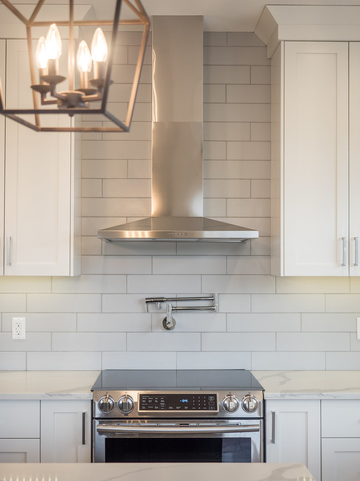 Inspiration for a mid-sized transitional l-shaped vinyl floor and brown floor eat-in kitchen remodel in Calgary with a double-bowl sink, recessed-panel cabinets, white cabinets, granite countertops, white backsplash, ceramic backsplash, stainless steel appliances and an island