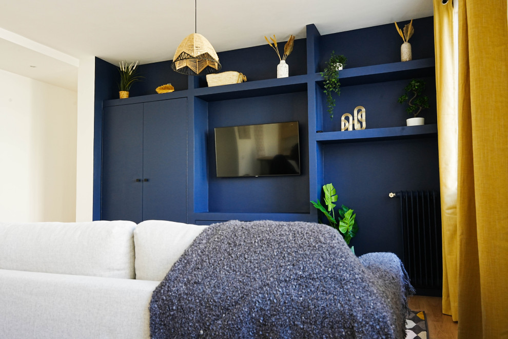 Esempio di un soggiorno minimal di medie dimensioni e aperto con libreria, pareti blu, parquet chiaro, nessun camino, parete attrezzata e pavimento beige