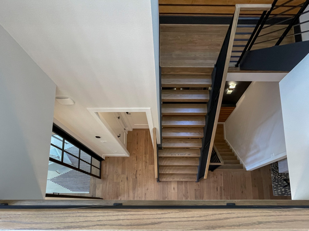Cette image montre un grand escalier droit design avec des marches en bois, un garde-corps en matériaux mixtes et du lambris.