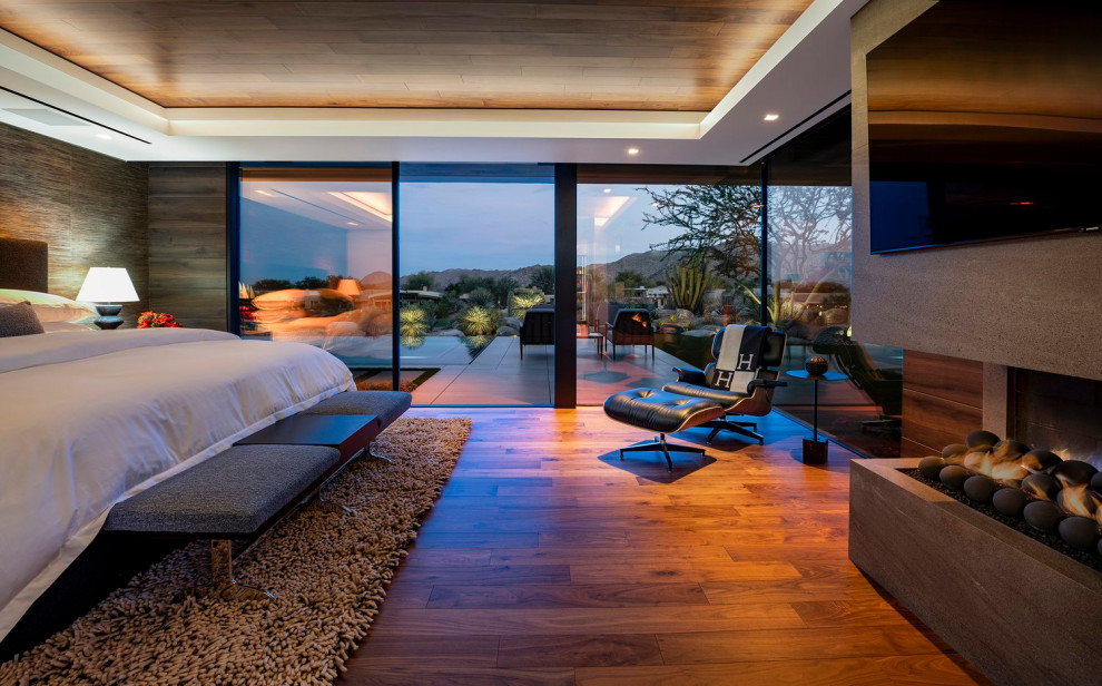 Großes Modernes Hauptschlafzimmer mit brauner Wandfarbe, Kamin, Kaminumrandung aus Stein, beigem Boden und eingelassener Decke in Los Angeles