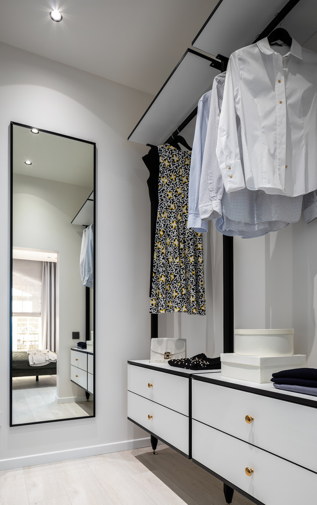 Photo of a small contemporary gender-neutral walk-in wardrobe in Other with flat-panel cabinets, white cabinets, laminate floors and beige floor.