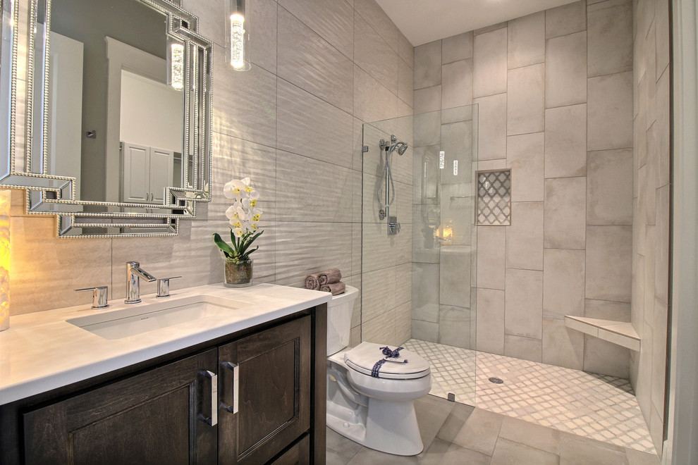Photo of an expansive transitional 3/4 bathroom in Portland with shaker cabinets, dark wood cabinets, a curbless shower, a bidet, gray tile, porcelain tile, beige walls, ceramic floors, an undermount sink, engineered quartz benchtops, beige floor, an open shower and white benchtops.