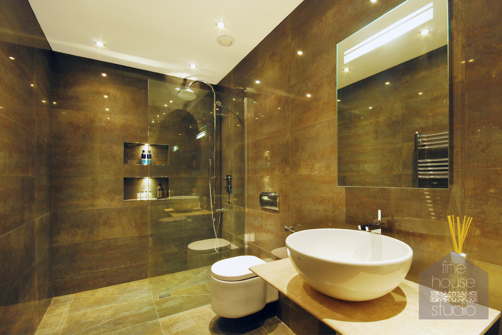 Design ideas for an expansive contemporary master bathroom in Gloucestershire with a vessel sink, limestone benchtops, an open shower, a wall-mount toilet, brown tile, stone tile, brown walls and limestone floors.