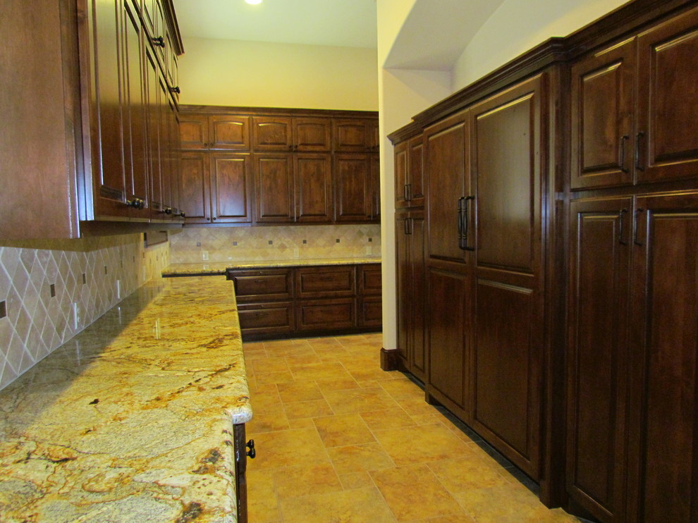 This is an example of a large country kitchen in Houston with raised-panel cabinets, dark wood cabinets, granite benchtops, porcelain splashback, stainless steel appliances, porcelain floors and with island.