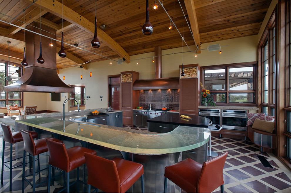 This is an example of a large contemporary u-shaped eat-in kitchen in Jacksonville with stainless steel appliances, an undermount sink, glass benchtops, multiple islands, stainless steel cabinets, recessed-panel cabinets, brown splashback, glass tile splashback, marble floors and multi-coloured floor.