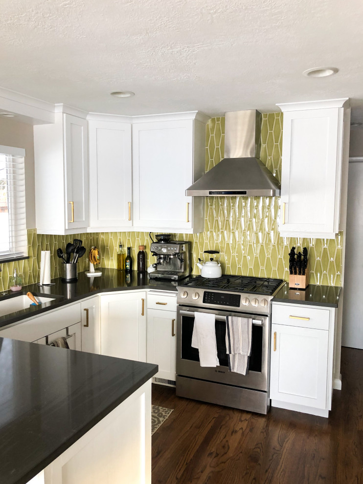 This is an example of a small modern l-shaped eat-in kitchen in Salt Lake City with a single-bowl sink, shaker cabinets, white cabinets, green splashback, ceramic splashback, stainless steel appliances, dark hardwood floors, no island, brown floor and black benchtop.