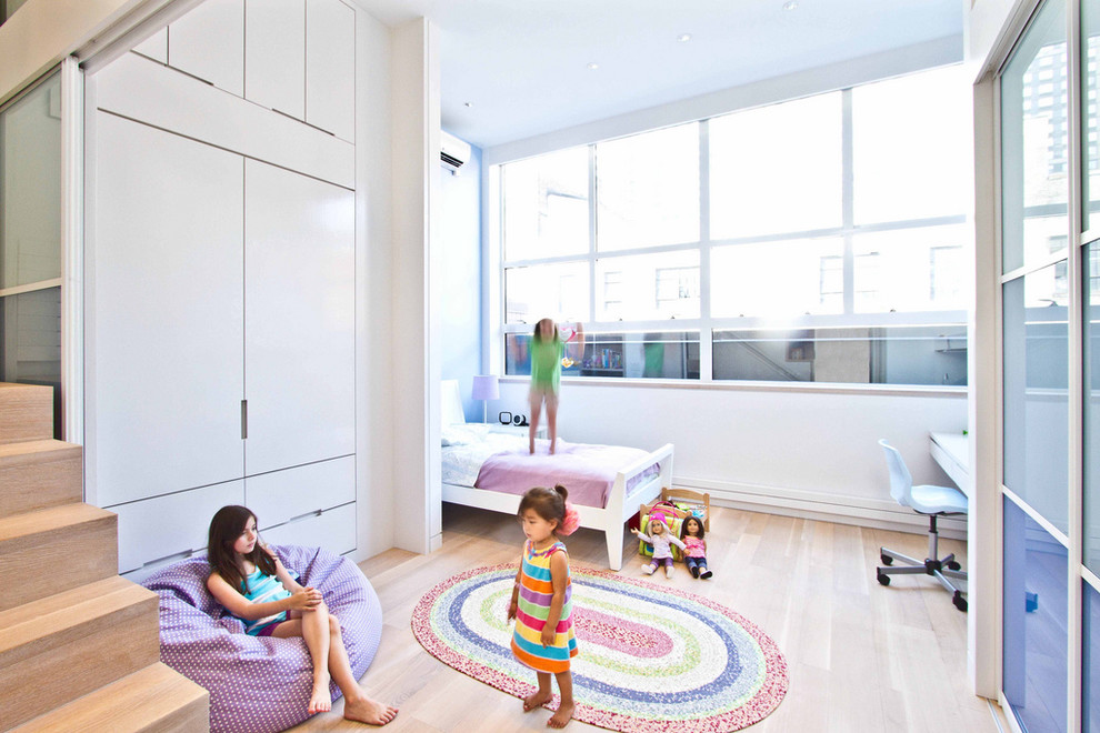 Inspiration for a modern kids' bedroom for kids 4-10 years old and girls in New York with white walls and light hardwood floors.