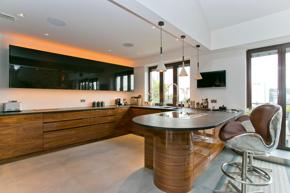 This is an example of a contemporary kitchen in London with concrete floors and a peninsula.