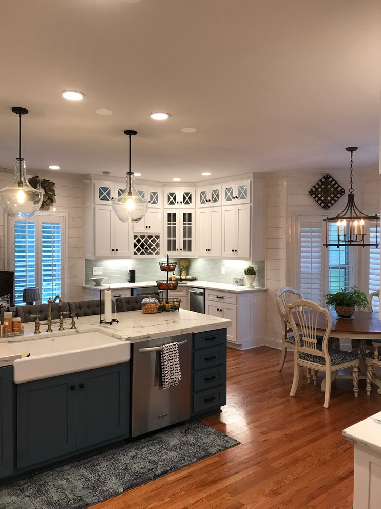 Eat-in kitchen - mid-sized transitional u-shaped medium tone wood floor and brown floor eat-in kitchen idea in Atlanta with an island, a farmhouse sink, shaker cabinets, white cabinets, stainless steel appliances, subway tile backsplash and quartz countertops
