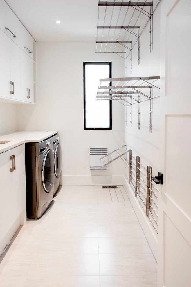 Photo of a contemporary single-wall dedicated laundry room in Ottawa with flat-panel cabinets, white cabinets, quartz benchtops, white walls, ceramic floors, a side-by-side washer and dryer and an undermount sink.