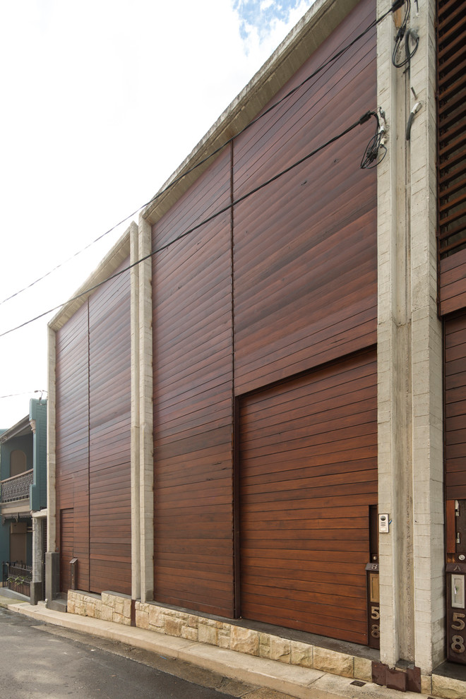 This is an example of a mid-sized industrial three-storey brown townhouse exterior in Sydney with wood siding and a flat roof.