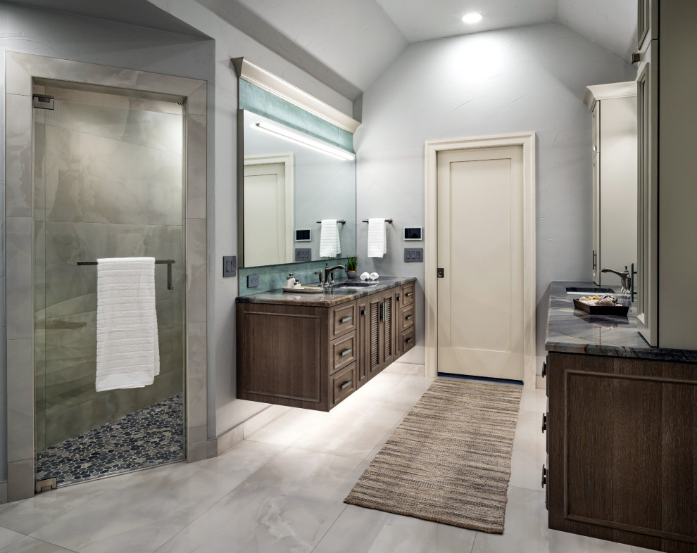 Photo of a world-inspired ensuite bathroom in Oklahoma City with louvered cabinets, brown cabinets, a freestanding bath, a built-in shower, a one-piece toilet, white tiles, porcelain tiles, grey walls, porcelain flooring, a submerged sink, quartz worktops, white floors, an open shower, multi-coloured worktops, a shower bench, double sinks and a floating vanity unit.