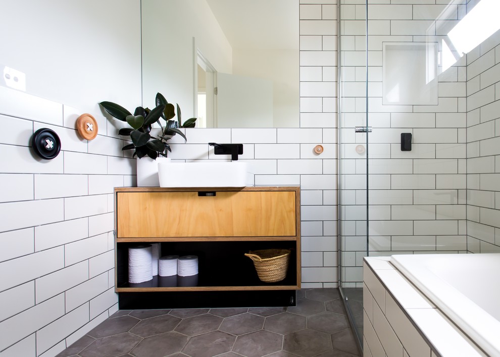 Photo of a mid-sized scandinavian bathroom in Melbourne with light wood cabinets, a drop-in tub, a corner shower, white tile, subway tile, a vessel sink, wood benchtops, grey floor and brown benchtops.