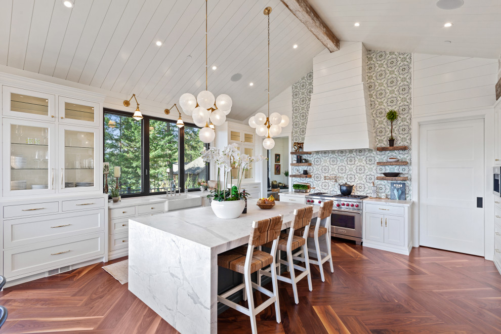 Inspiration for a transitional u-shaped eat-in kitchen in Other with a farmhouse sink, shaker cabinets, white cabinets, marble benchtops, multi-coloured splashback, cement tile splashback, stainless steel appliances, medium hardwood floors, with island, brown floor and white benchtop.