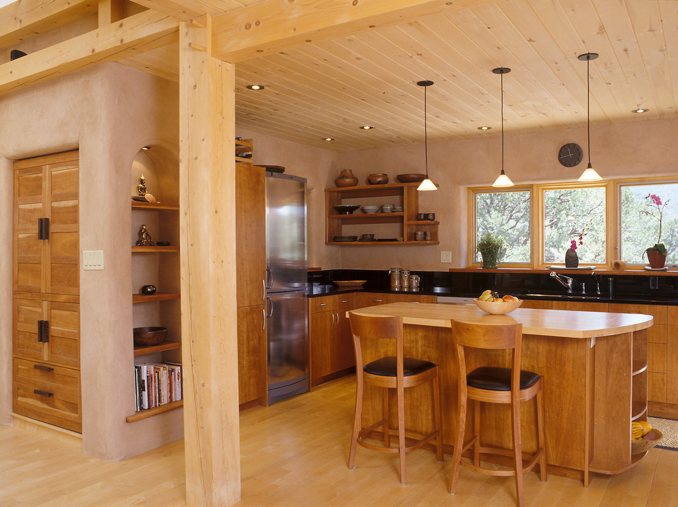 This is an example of an asian kitchen in Portland with flat-panel cabinets, medium wood cabinets and stainless steel appliances.