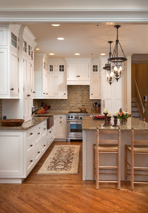 Bright white shaker RTA cabinets in a classic kitchen with granite countertops, brick tile backsplash, island seating, and hardwood floors.