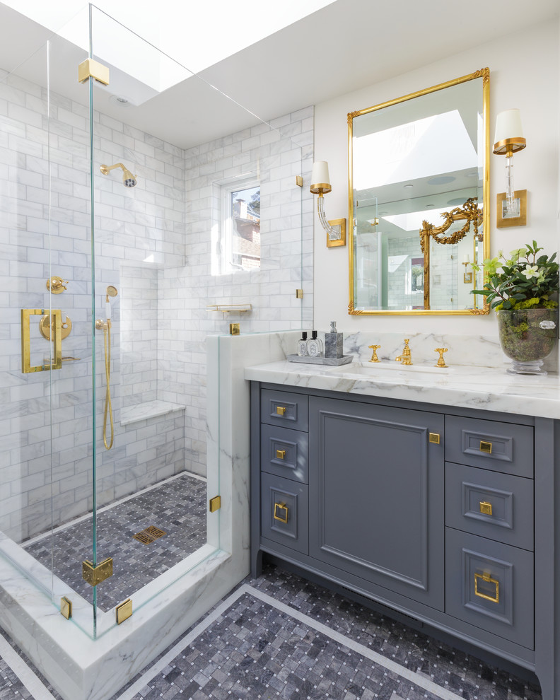 This is an example of a mid-sized traditional bathroom in San Francisco with grey cabinets, a corner shower, white tile, marble, white walls, mosaic tile floors, an undermount sink, grey floor, a hinged shower door, a shower seat and recessed-panel cabinets.