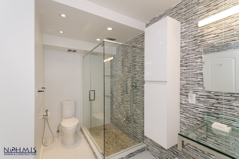 Mid-sized contemporary master bathroom in Miami with glass-front cabinets, brown cabinets, a corner tub, a shower/bathtub combo, a bidet, gray tile, matchstick tile, grey walls, ceramic floors, an integrated sink and marble benchtops.