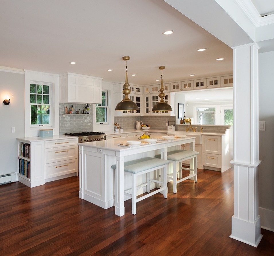 Mid-sized traditional l-shaped eat-in kitchen in Other with a farmhouse sink, recessed-panel cabinets, white cabinets, quartz benchtops, blue splashback, stainless steel appliances, medium hardwood floors, with island, brown floor and white benchtop.
